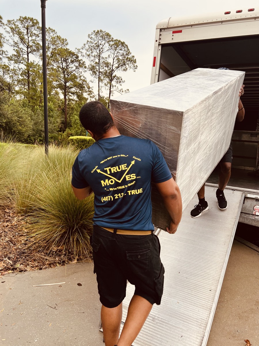 Crew loading a large wrapped piece up the ramp